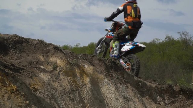Professional motor biker jumping over in slow motion on a motocross track.