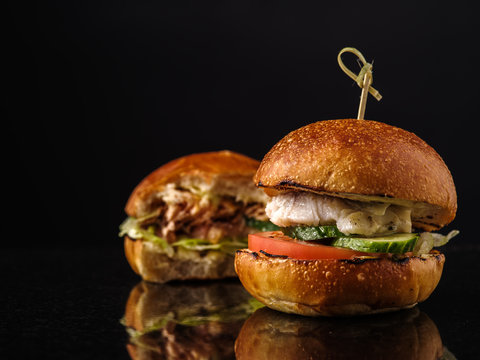 Fresh Fish burger with vegetables on a dark background.