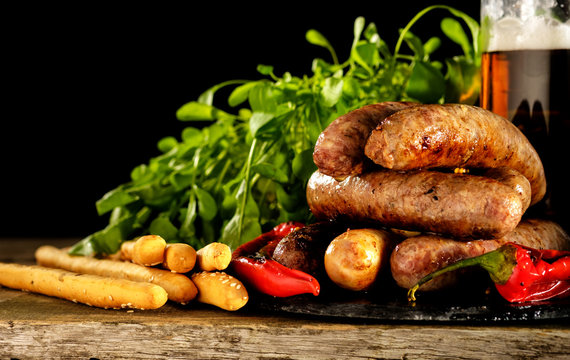Grilled sausages with a glass of beer on a wooden table