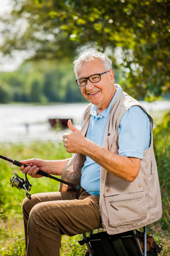 Happy senior man is fishing on sunny day..