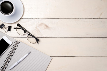 White set. Pen, eyeglasses, coffee and notebook on table. Top view.