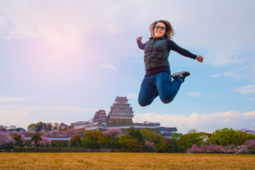 Asian lady girl jump in happy face at Himeji castle in Japan in Sakura cherry blossom seasom