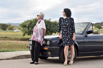 portrait of two women leaning on a car