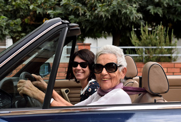 an older woman and a young woman driving a convertible