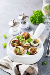 Bourgogne Escargot Snails with garlic herbs butter in white pan on light gray background. Healthy food concept.