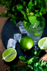 Mojito cocktail  with lime and mint  in a glass on a black  stone background with fresh  ingredients. Copy space.