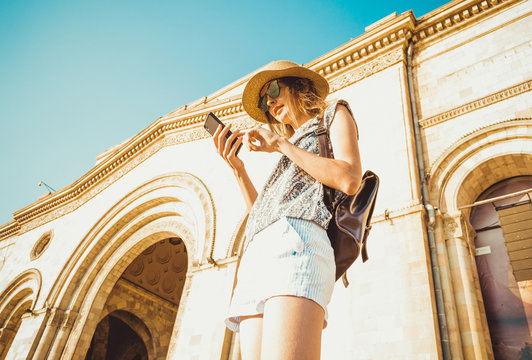 Young woman tourist in hat with backpack using gps navigation on phone. Online booking. Summer fashion style. City tour. Explore the world. Time to travel. Modern technology. Tourism concept. Yerevan