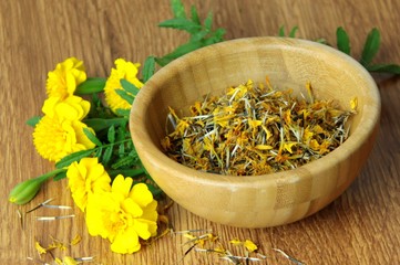 Tagetes flower and dried seeds in a wooden bowl.