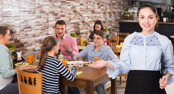 Professional waitress holding tray with dishes meeting visitors