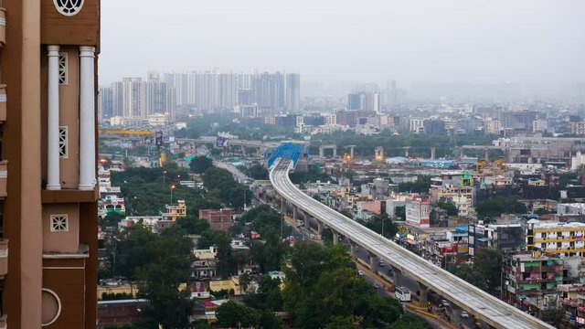 Zooming day to night timelapse showing the delhi cityscape. Shows buildings with lights, traffic, unfinished overhead metro tracks and the horizon in Delhi. A beautiful look at Delhi, Noida and