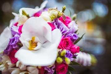 Wedding bouquet made of orchids and violet flowers lies on a car