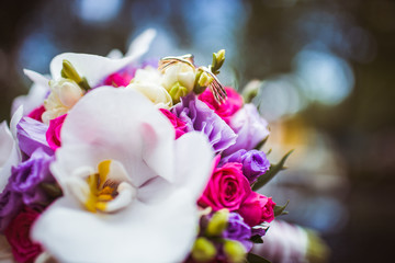 Wedding bouquet made of orchids and violet flowers lies on a car