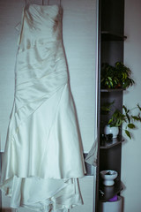 White wedding dress hangs before a door