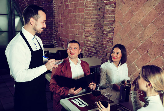 Man waiter receiving order from guests