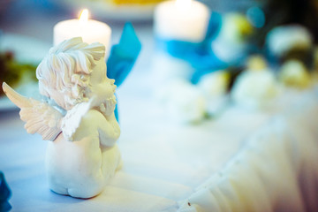 Porcelain angel sits before a candle on dinner table