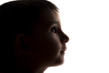 silhouette of a small boy face looking upwards, kids head profile
