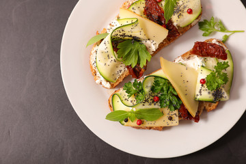 bread sliced with cheese, cucumber and dried tomato