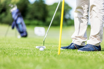 Obraz premium Golfer putting ball in the hole on a golf course.