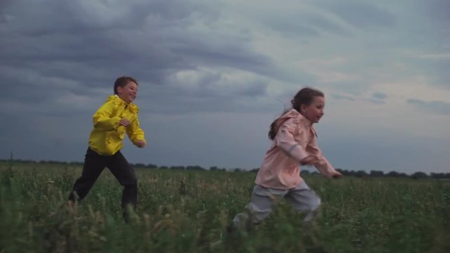 cute children having pleasure running on nature under cloudy sky in cold season slomo