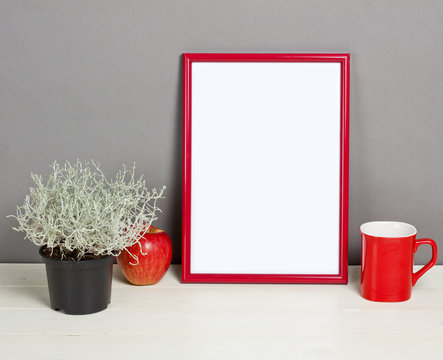 Red frame mockup with plant pot, mug and apple on wooden shelf