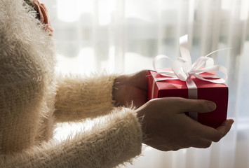 Young woman hands holding red gift box with white ribbon for christmas and new year and other celebration