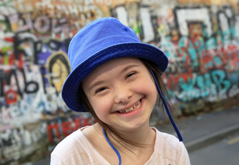Cute smiling down syndrome girl on the background of the graffiti wall