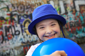 Cute smiling down syndrome girl on the background of the graffiti wall
