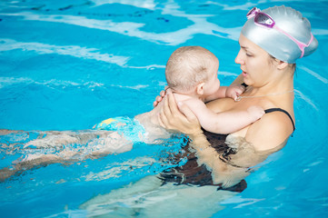 Happy little boy having fun with his mother in a swimming pool