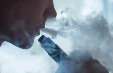 vaping man holding a mechanical mod. A cloud of vapor.