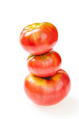 Red tomatoes on top of big delicious tomato, isolated on white. Pyramid of red tomatoes