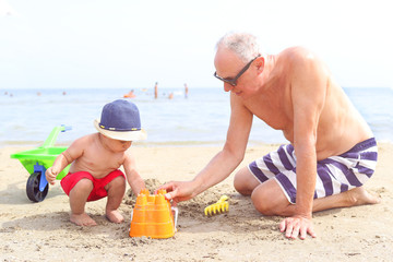 Little boy and grandfather playing at the beach