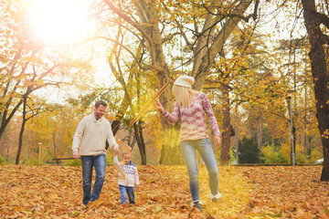 Fototapeta premium Mother and father playing with son in park at autumn/ flying kite