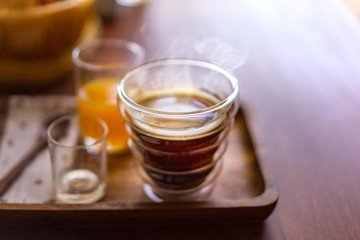 Hot americano coffee with orange juice on wooden table.