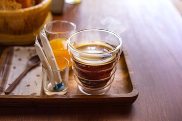 Hot americano coffee with orange juice on wooden table.