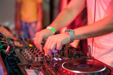 Fototapeta na wymiar DJ playing music at mixer on colorful blurred background