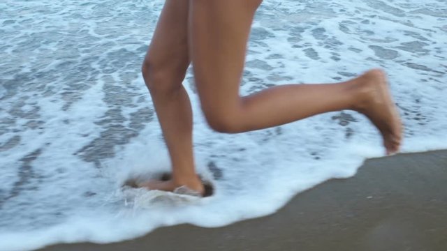Little girls run barefoot on the sand beach. Slow motion.
