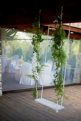 Wedding swing decorated with flowers hanging on the branches of the old willow