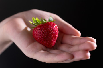 Strawberry in hand with dark background