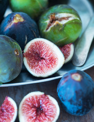 Whole and sliced figs on a plate and on a wooden table. Beautiful still life.