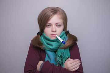 Young caucasian woman is sick and keeps a thermometer in her mouth