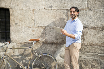 Obraz na płótnie Canvas man smiling using internet with digital tablet pad on vintage cool retro bike
