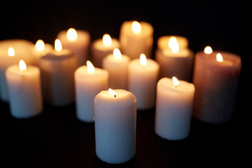 Fototapeta na wymiar candles burning in darkness over black background