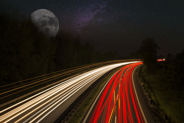 Trails on highway with stars and moon