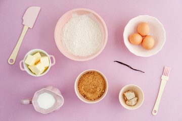 Flatlay collection of tools and ingredients for home baking on pink background shot from above
