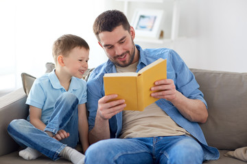 happy father and son reading book sofa at home