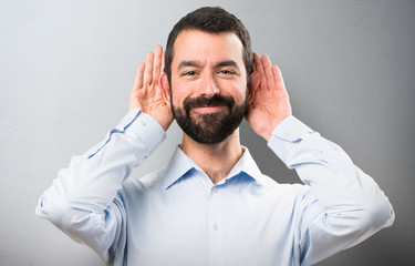 Handsome man with beard listening something on textured background