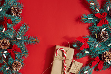 Christmas composition of pine cones, spruce branches and stack of gift boxes on red background