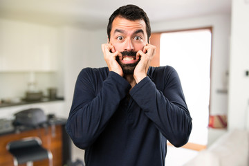 Frightened handsome man with beard inside house