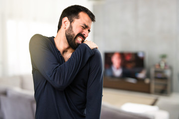 Handsome man with beard with shoulder pain inside house