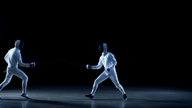Two Professional Fencers Fully Equipped Expertly Fight with Foils. Shot Isolated on Black Background  with Blue Tones.